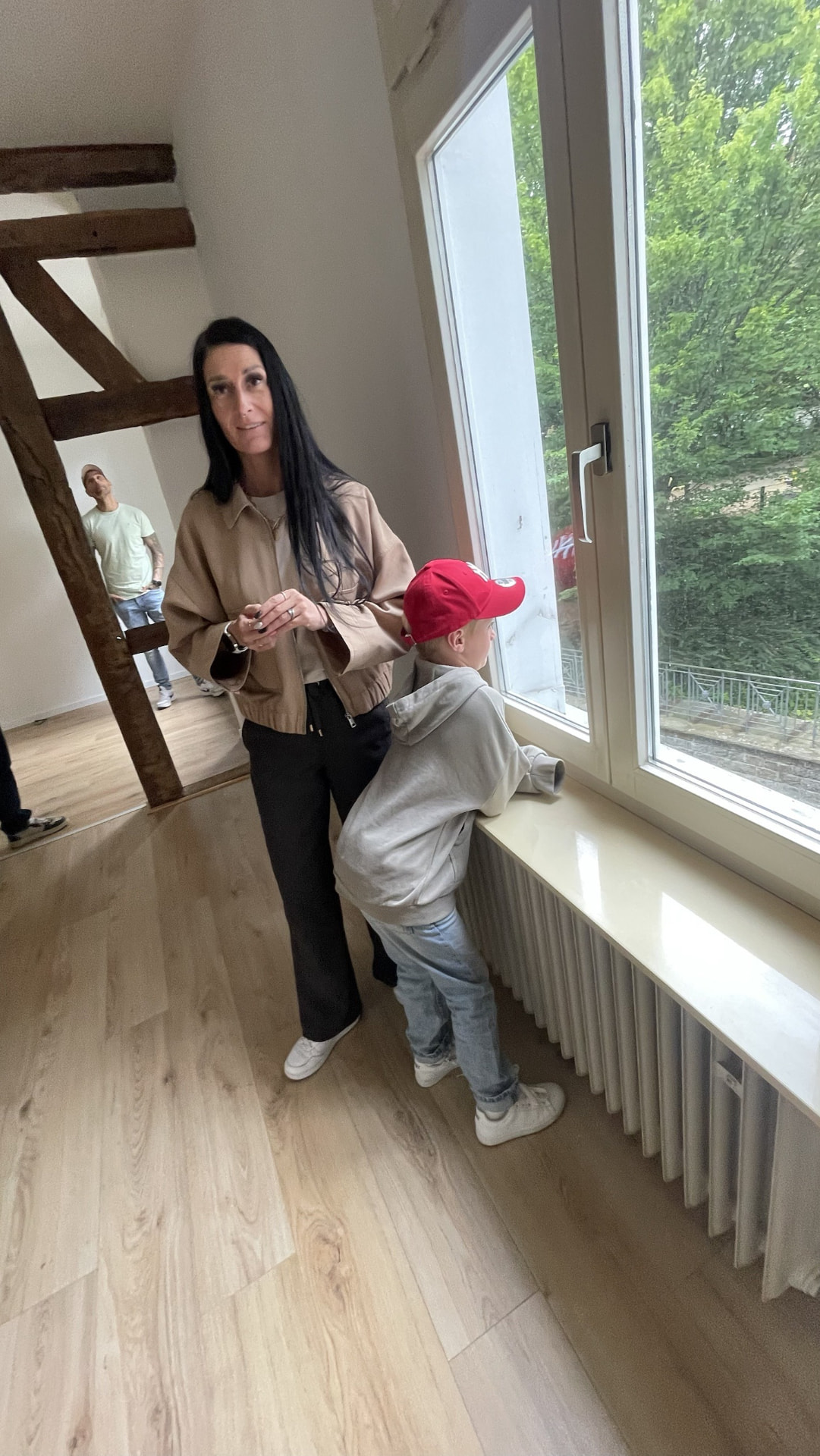 Manuela und ihr Sohn schauen aus dem Fenster der neuen Wohnung